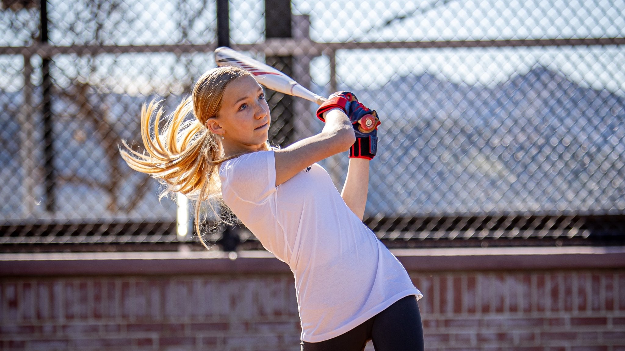 Young girl preparing to hit a ball with a bat on a sports field.