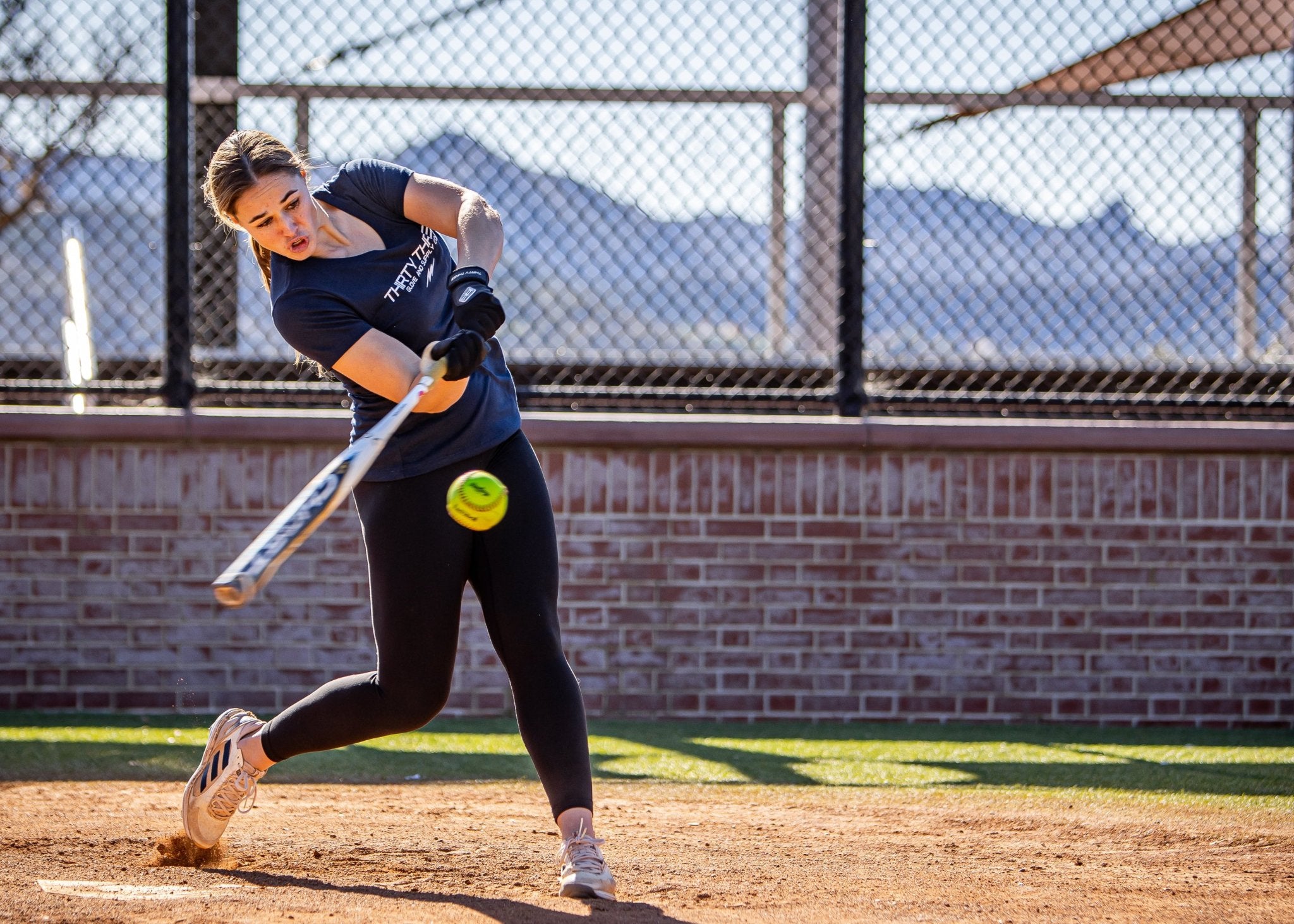 Woman playing softball on a field with mountains in the background