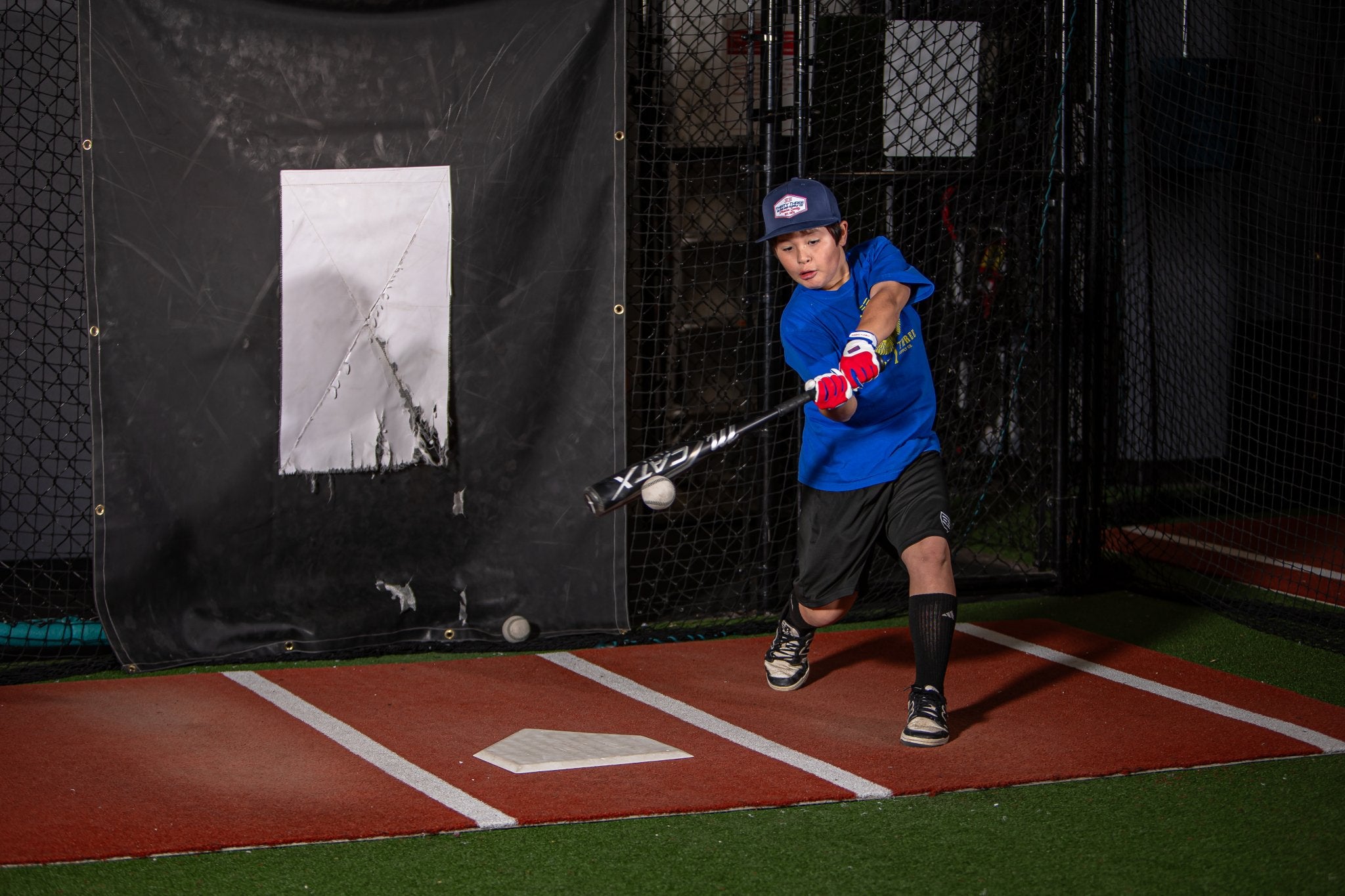 Child practicing batting in a batting cage