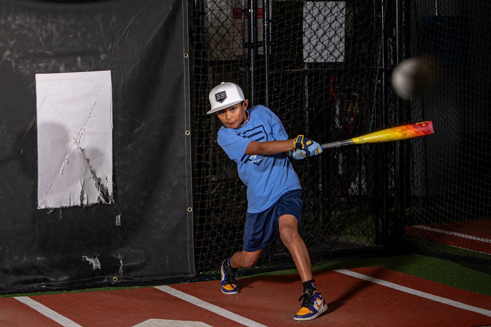 Person swinging a baseball bat in a batting cage